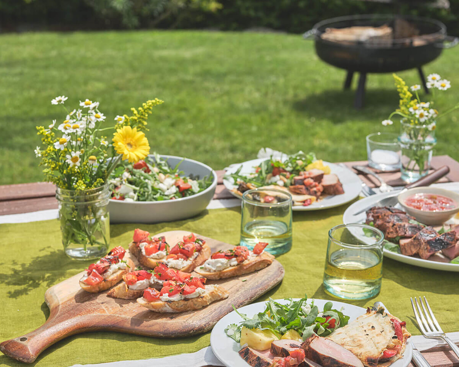picnic table with plates full of grilled food