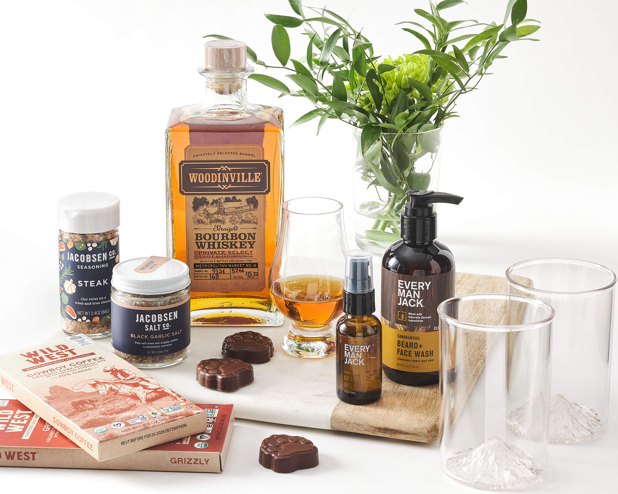 Whiskey, chocolate, seasonings, bottles, and greenery on a cutting board