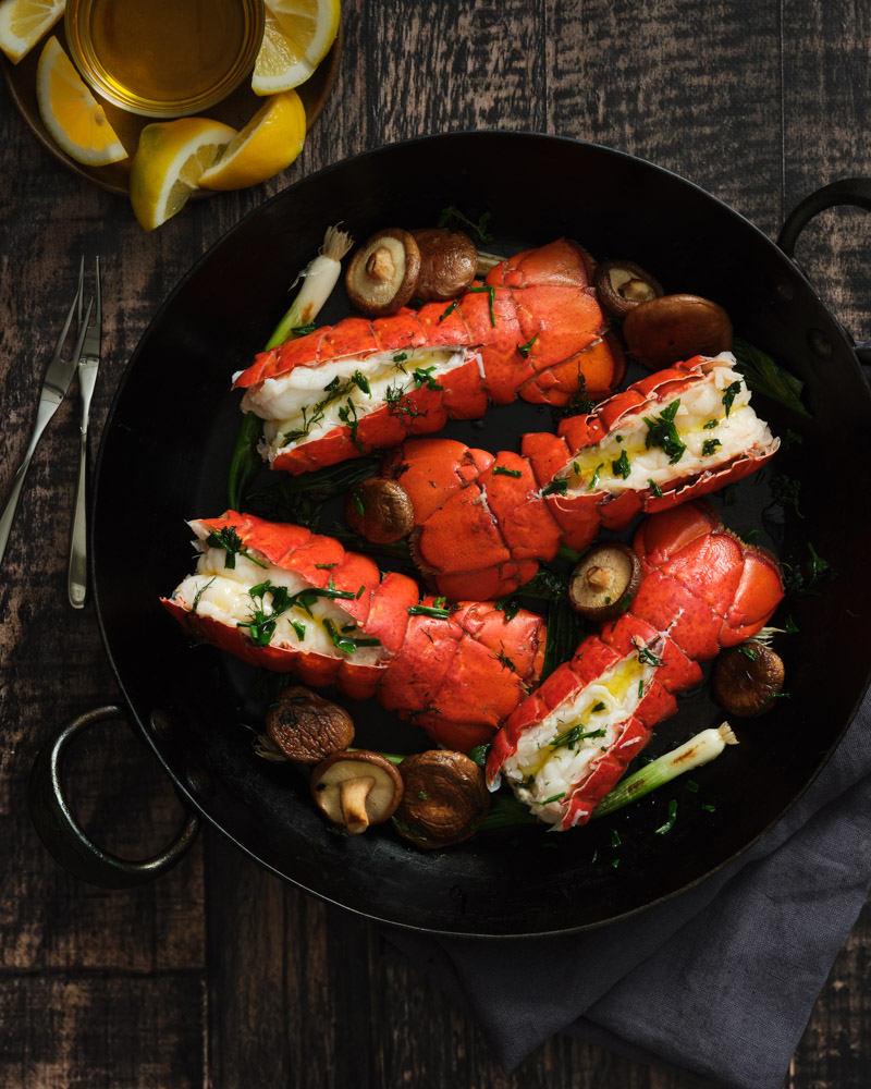 Cooked lobster in cast iron pan with lemons