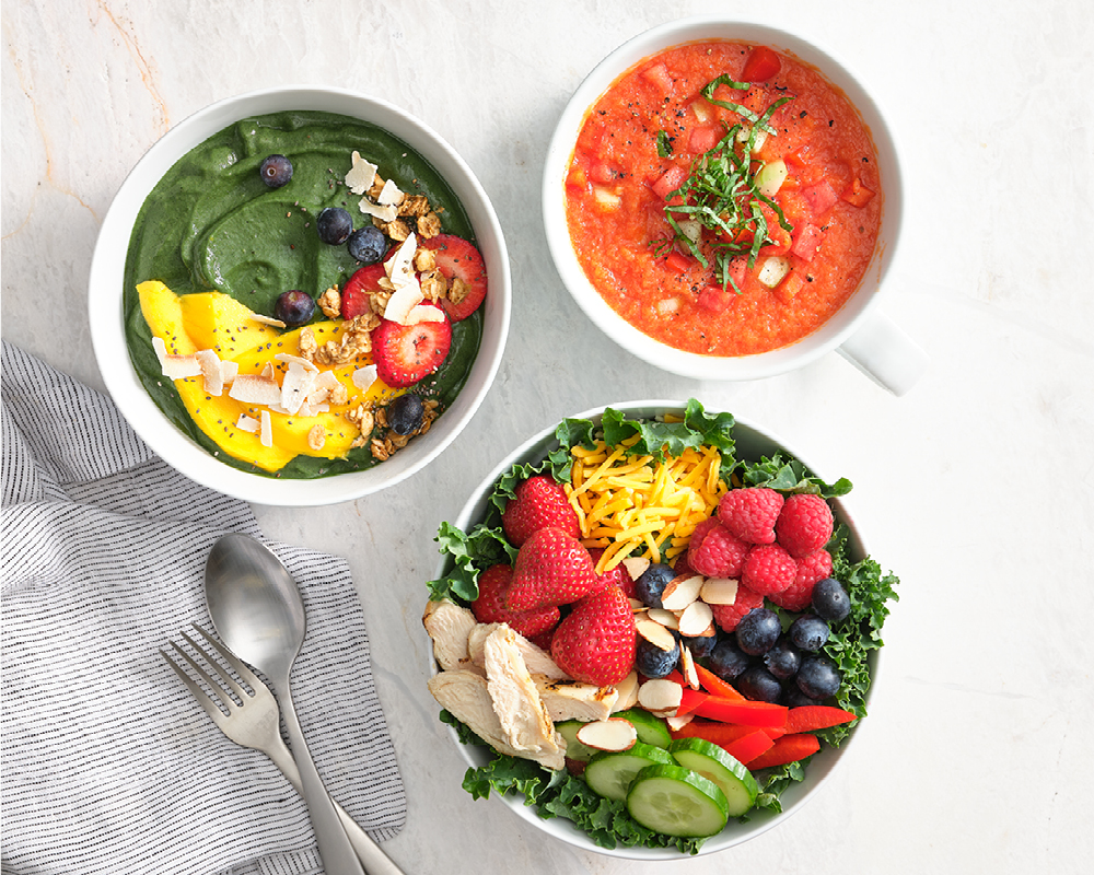 Three colorful bowls filled with fresh produce and soup