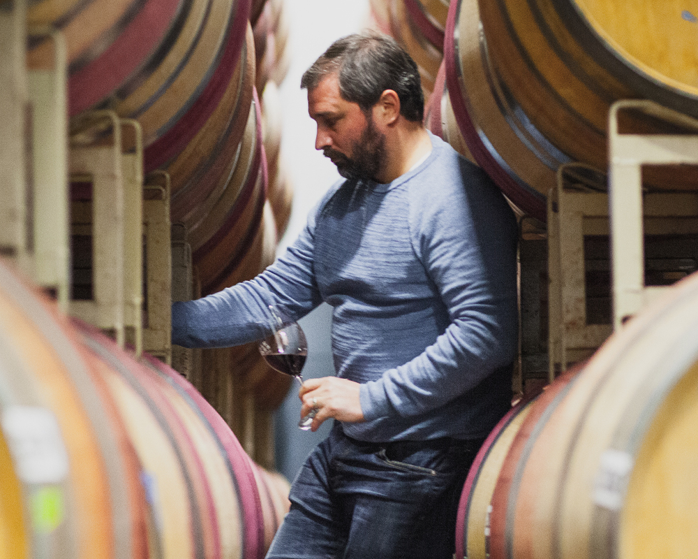 Jason Gorski standing in the middle of rows of wine barrels