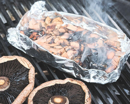mushrooms grilling and smoking on a grill